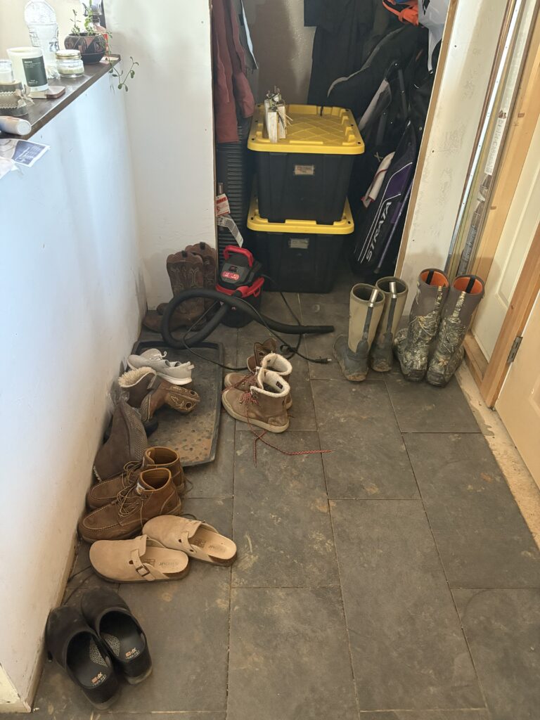 Back door entry piled with shoes, bags, and coats, a sign of a flow problem, not a small house