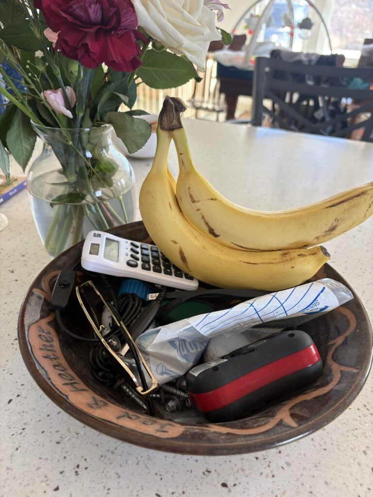Kitchen island covered in mail, keys, and a backpack from a pinched entry with no drop zone
